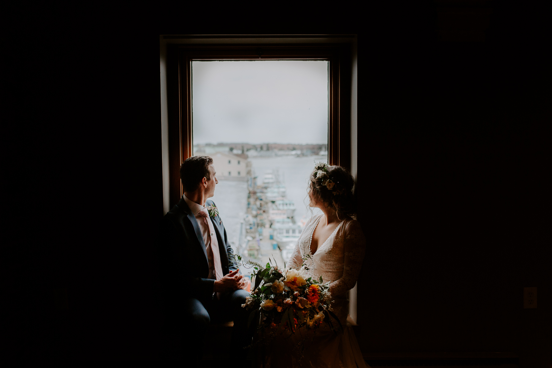 A bride and groom look out over the boats in Portland Harbor in Portland, Maine 
